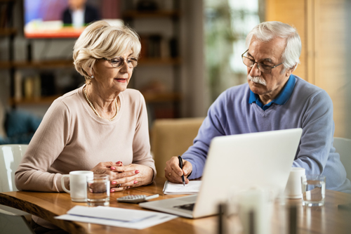 Mature couple using computer while planning their home budget.